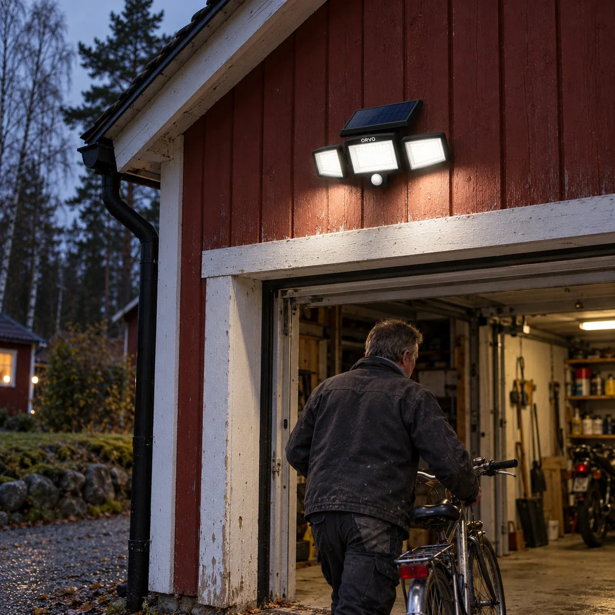 Närbild på Orvo solcellslampa på en ljus träfasad: solpanel, tre LED-huvuden och rörelsesensor